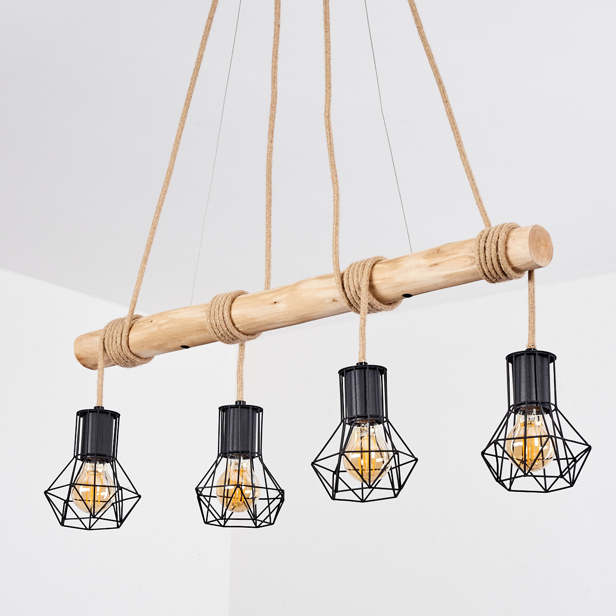 Eine rustikale Hängelampe mit vier schwarzen geometrischen Lampen, die an einem Holzbalken und Seilen hängen, vor weißem Hintergrund.