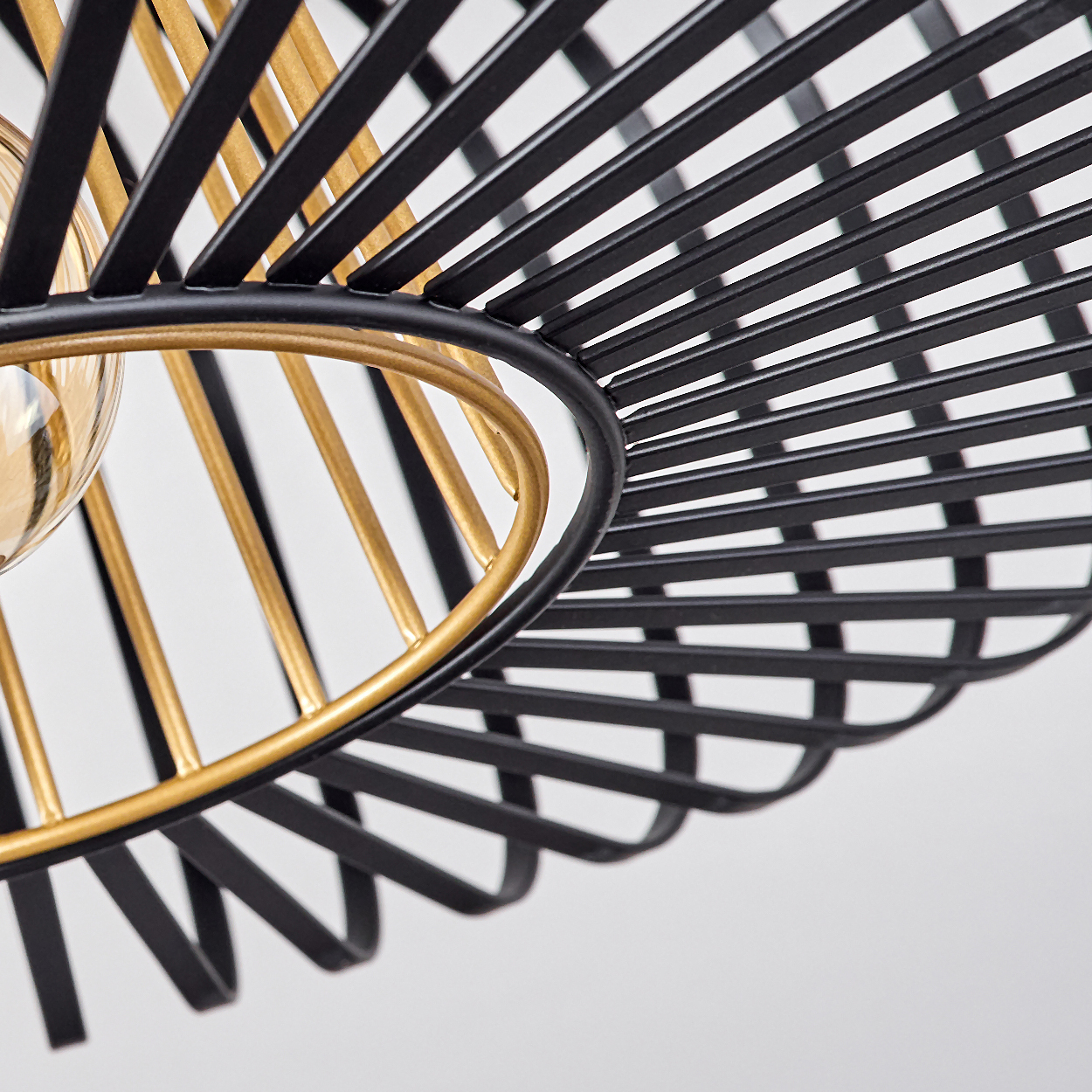 Nahaufnahme einer schwarz-goldenen Metalllampe. Die Lampe hat eine kugelförmige Glühbirne und einen käfigartigen Schirm.