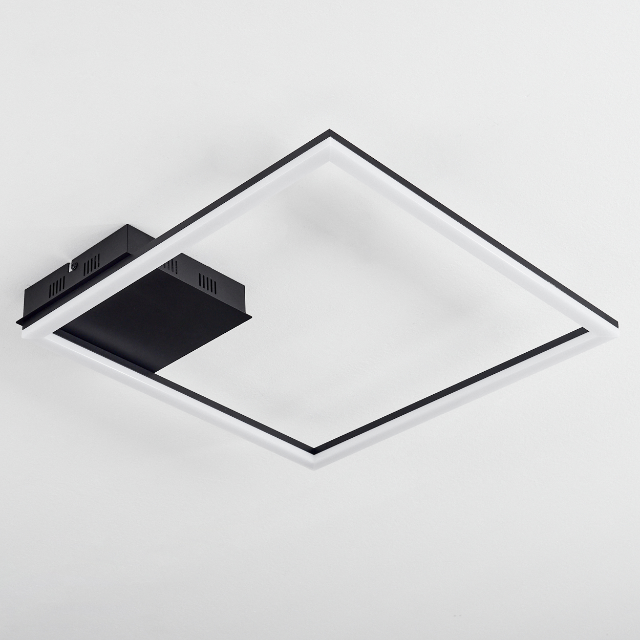 Eine Deckenleuchte mit quadratischem Design, schwarzem Rahmen und weißem Innenraum, an einer weißen Decke montiert.