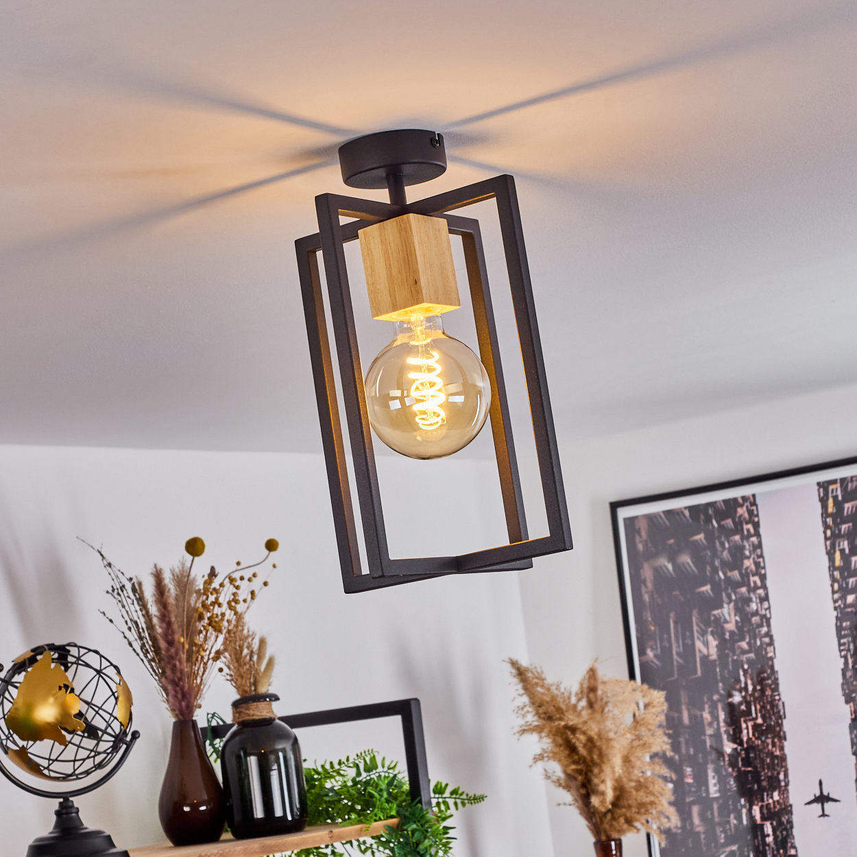 Eine moderne Deckenlampe mit Holzblock und großer Glühbirne. Dekorative Elemente auf einem Regal darunter, darunter ein Globus und Vasen.