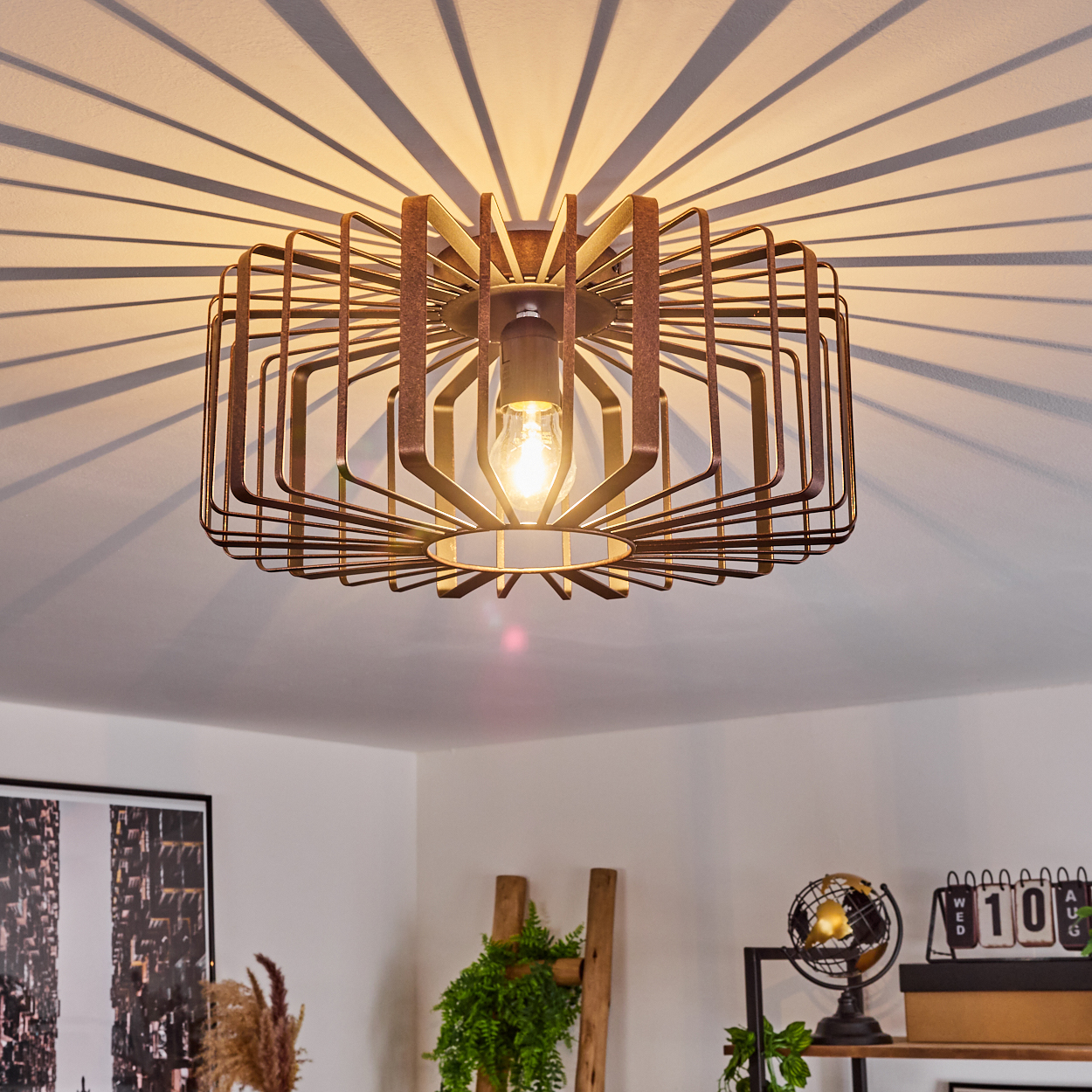 Eine geometrische Deckenlampe mit radialen Schatten. Der Raum hat dekorative Gegenstände wie Leiter, Pflanzen und Globus.
