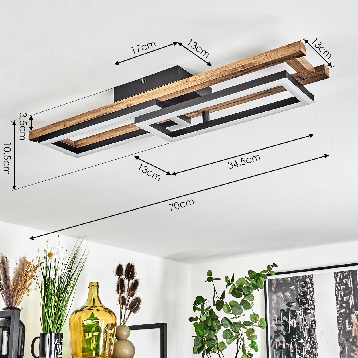 Eine Deckenleuchte mit Holzrahmen und rechteckigen Lichtpaneelen. Maße sind beschriftet. Dekorative Gegenstände sind unten.