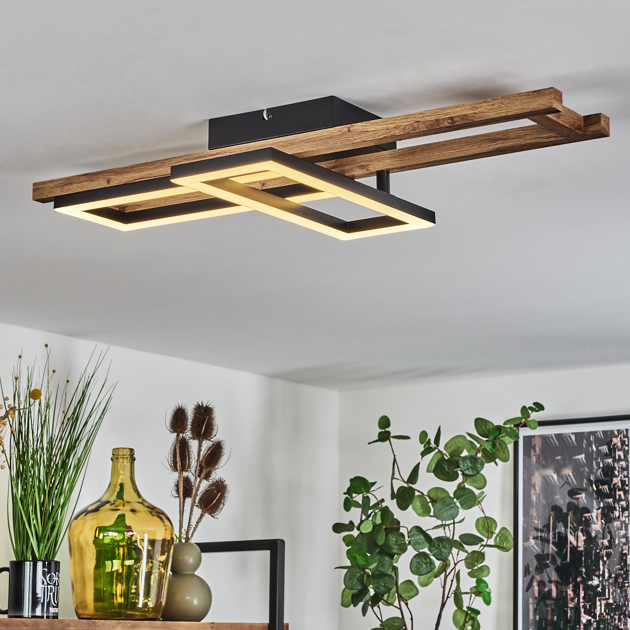 Eine moderne Deckenleuchte mit Holz- und schwarzen Rahmen. Darunter befindet sich ein Regal mit Vasen und Pflanzen.