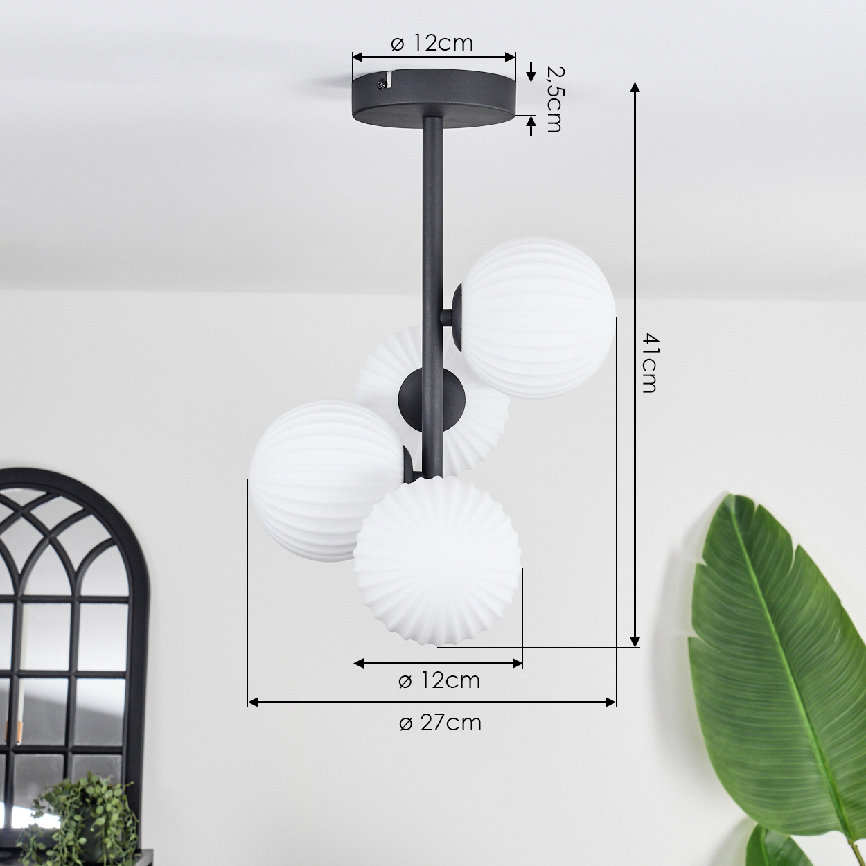 Eine schwarze Deckenlampe mit vier weißen Kugelschirmen. Abmessungen sind mit Pfeilen angegeben, die Größen in cm zeigen.