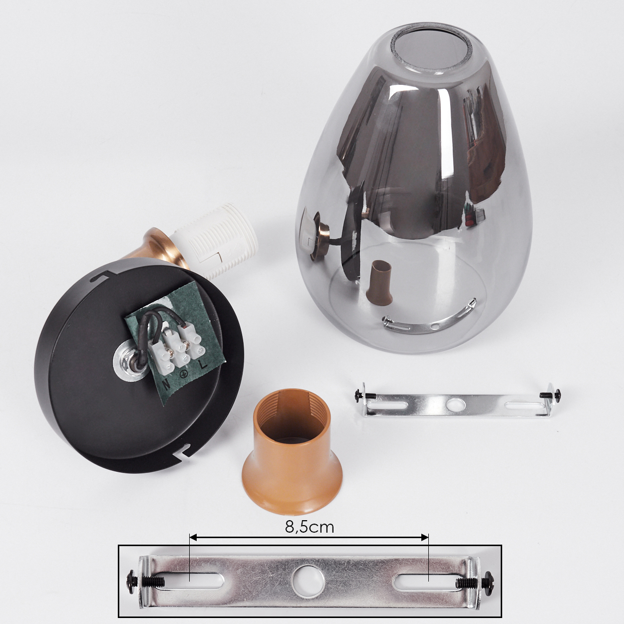 Zerlegte Lampenteile: schwarzer Sockel, Glasschirm, braune Fassung und Befestigungsmaterial. Abmessungen sind auf einem Metallstück angegeben.