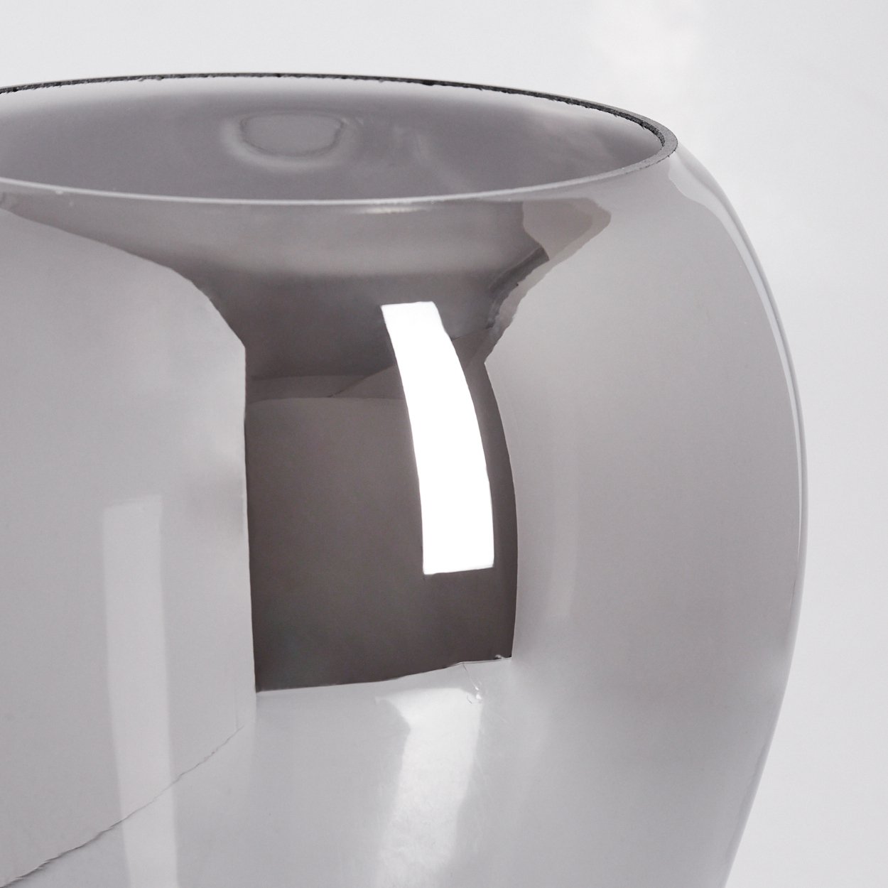 Eine graue Glasvase vor weißem Hintergrund. Die Vase hat eine breite, runde Form mit glänzender Oberfläche.