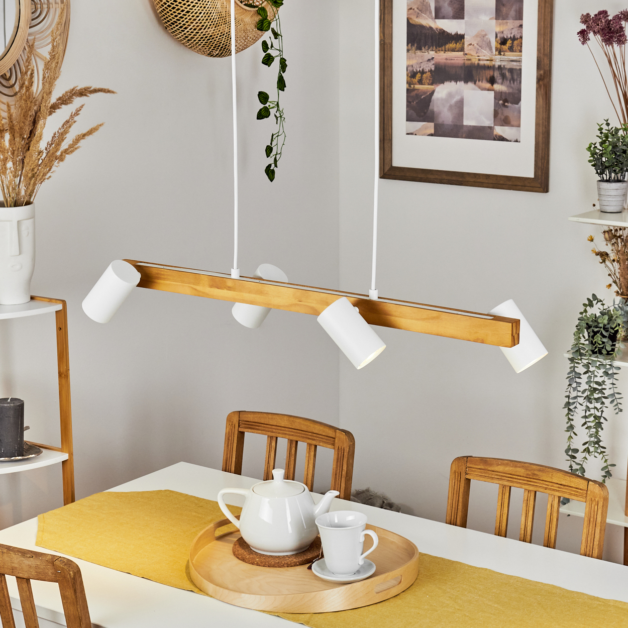 Esszimmer-Szene. Weißer Tisch, gelber Läufer, Teeservice auf Tablett, Holzstühle, Holzbalkenlicht und Wanddekorationen.