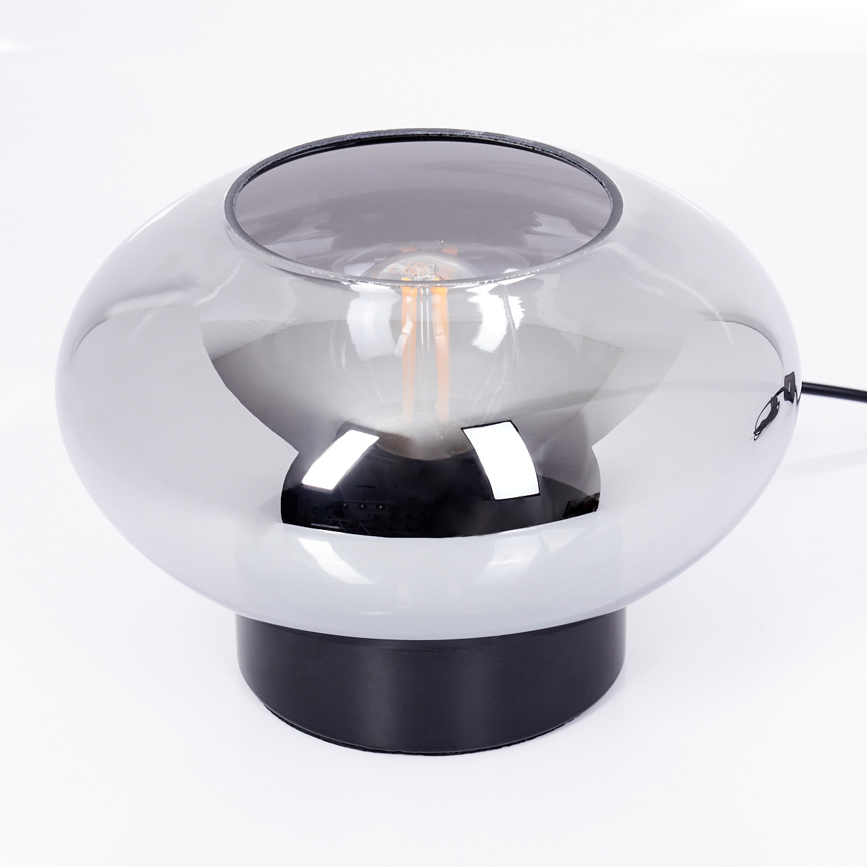 Eine moderne Tischlampe. Sie hat einen metallischen, kugelförmigen Schirm über einem schwarzen Sockel. Im Inneren des Schirms ist eine freiliegende Glühbirne zu sehen.