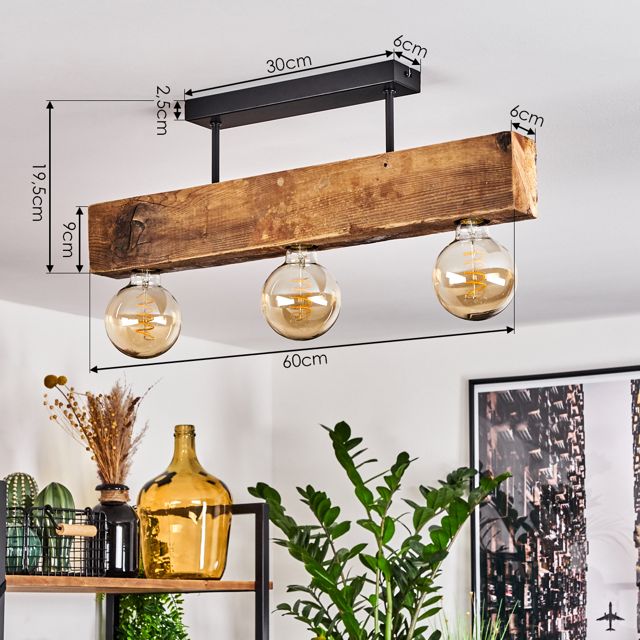 Ein Holzbalken mit drei kugelförmigen Glühbirnen hängt von der Decke. Darunter sind Pflanzen und dekorative Gegenstände auf einem Regal zu sehen.