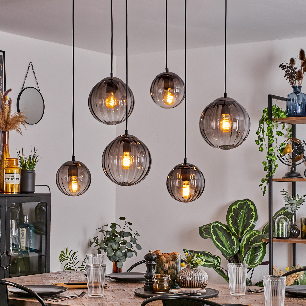 Esszimmer mit sechs h ängenden Kugelleuchten. Ein Holztisch ist zum Abendessen gedeckt. Pflanzen und Dekorationen sind im Hintergrund.