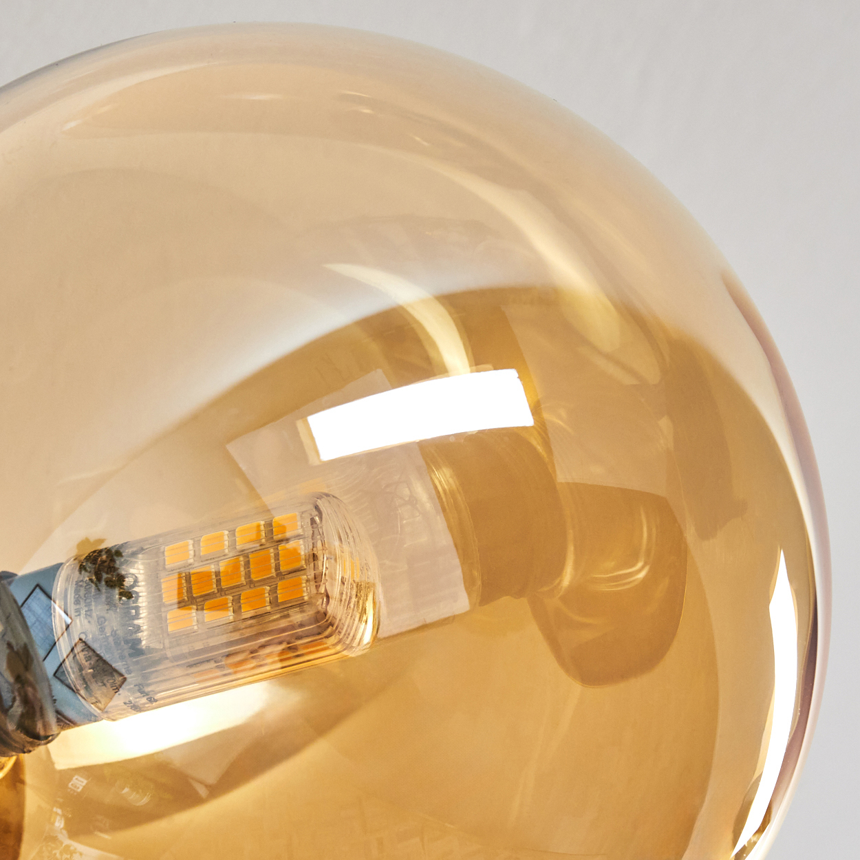 Nahaufnahme einer Glühbirne, die die inneren Komponenten zeigt. Das Glas ist bernsteinfarben und ein rechteckiges LED-Array ist sichtbar.