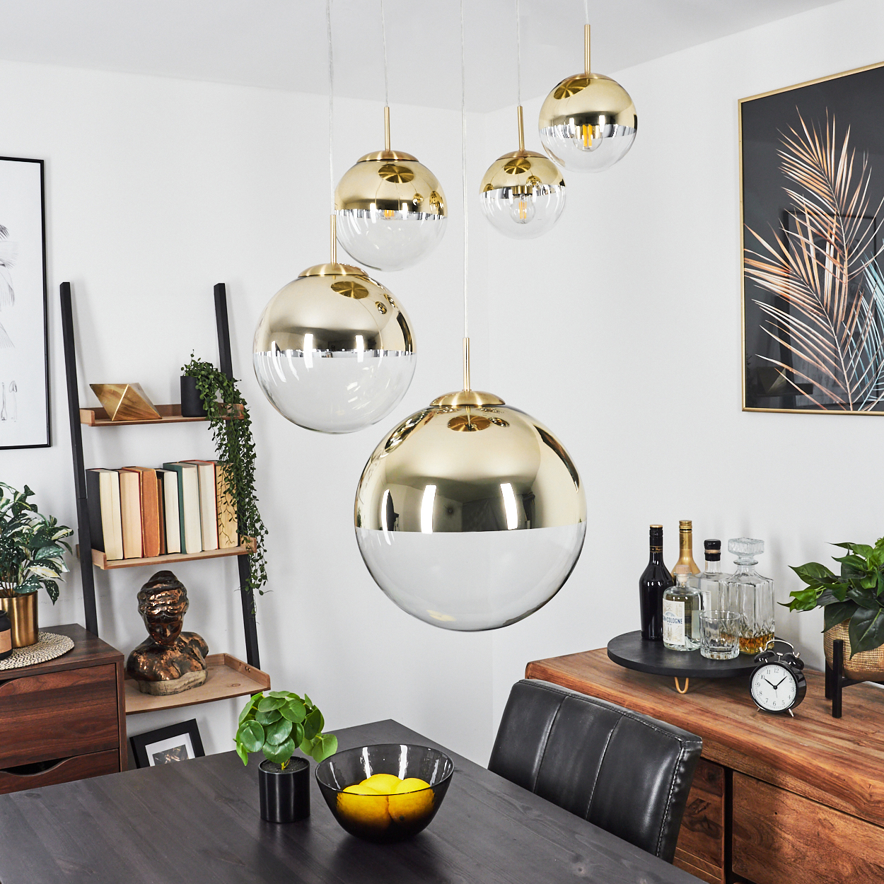 Ein Esszimmer mit dunklem Tisch, goldenen Lampen und einem Holzschrank. Eine Schüssel mit Zitronen steht auf dem Tisch. Schwarze Lederstühle.