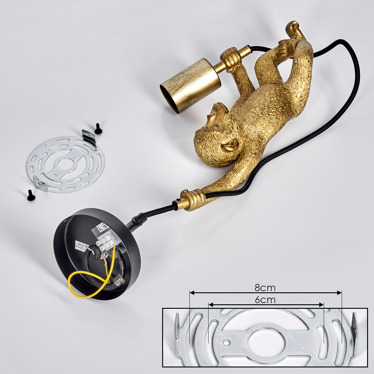 Eine goldene affenförmige Lampenhalterung, elektrische Komponenten, Montagematerial und ein Größenvergleich liegen auf weißem Untergrund.