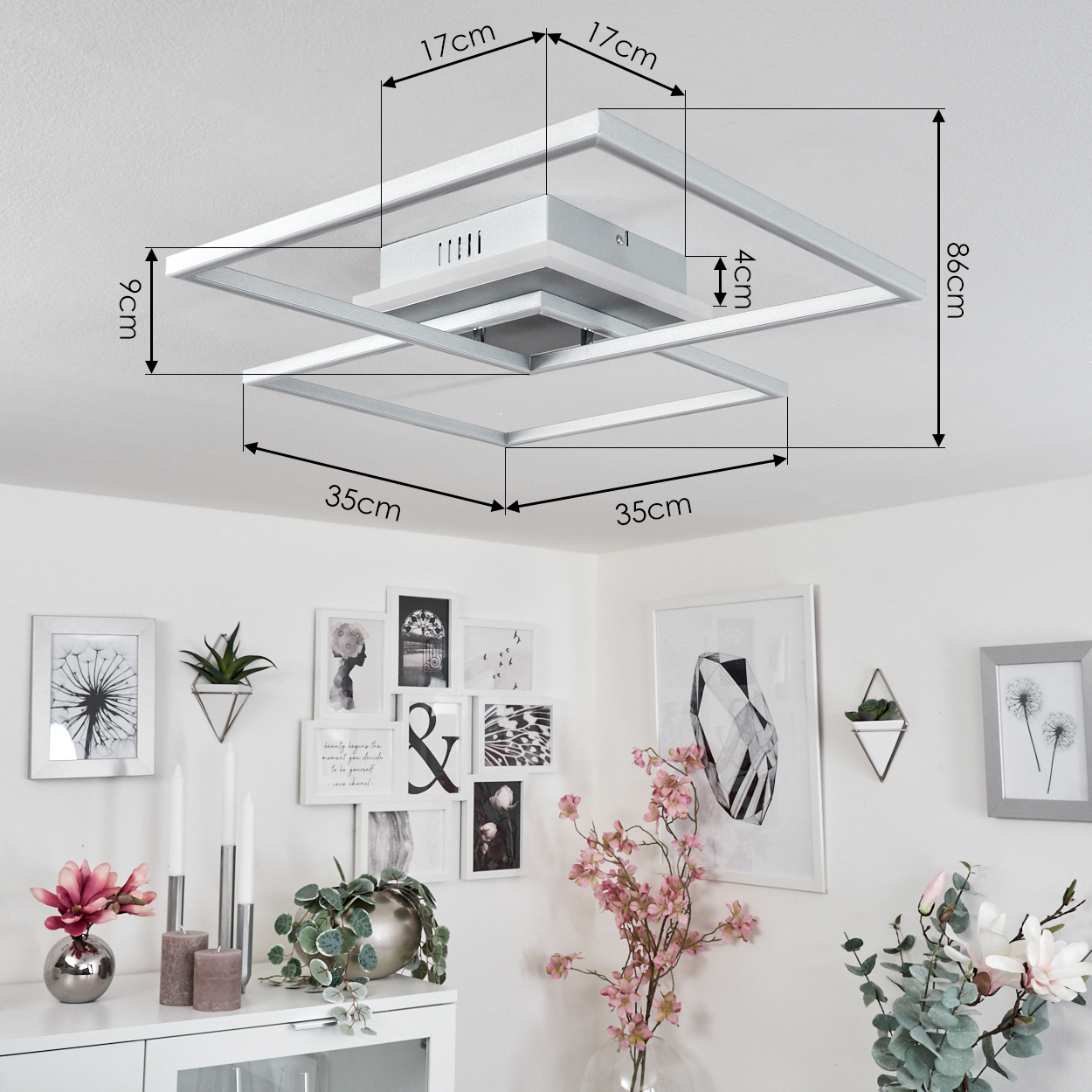 Eine Deckenleuchte und dekorative Wandkunst. Das Zimmer hat weiße Wände und einen weißen Schrank mit Blumen und Pflanzen.