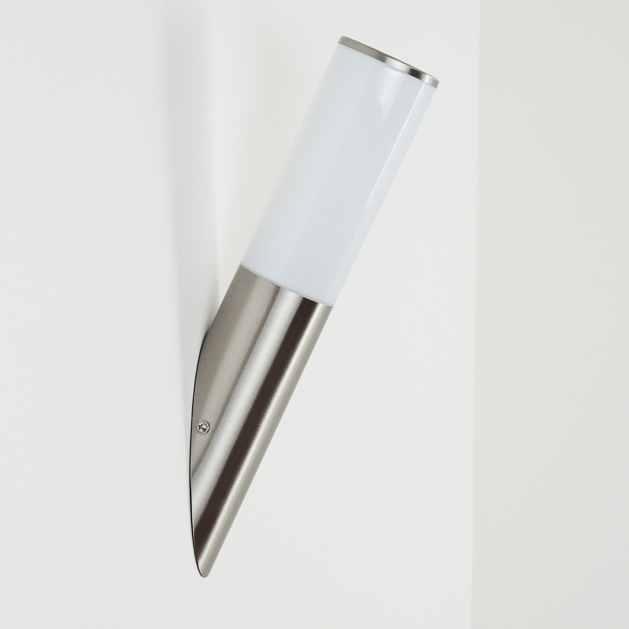 Eine moderne Wandleuchte mit weißem, zylindrischem Licht und silberfarbenem Metallsockel, montiert an einer weißen Wand.