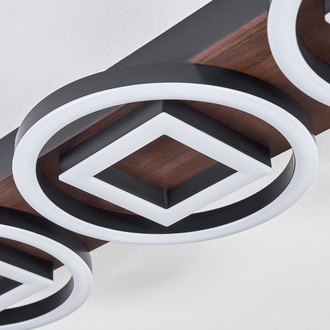 Nahaufnahme einer modernen Deckenleuchte. Sie hat geometrische Formen in Schwarz und Weiß und einen Hintergrund mit Holzmaserung.