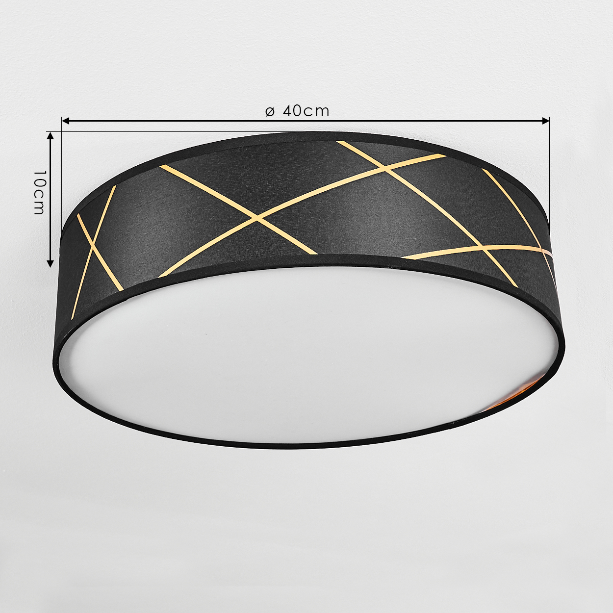 Eine schwarze Deckenlampe mit goldenen Linien und weißem Sockel. Maße sind 40 cm Durchmesser und 10 cm Höhe. An einer weißen Wand montiert.