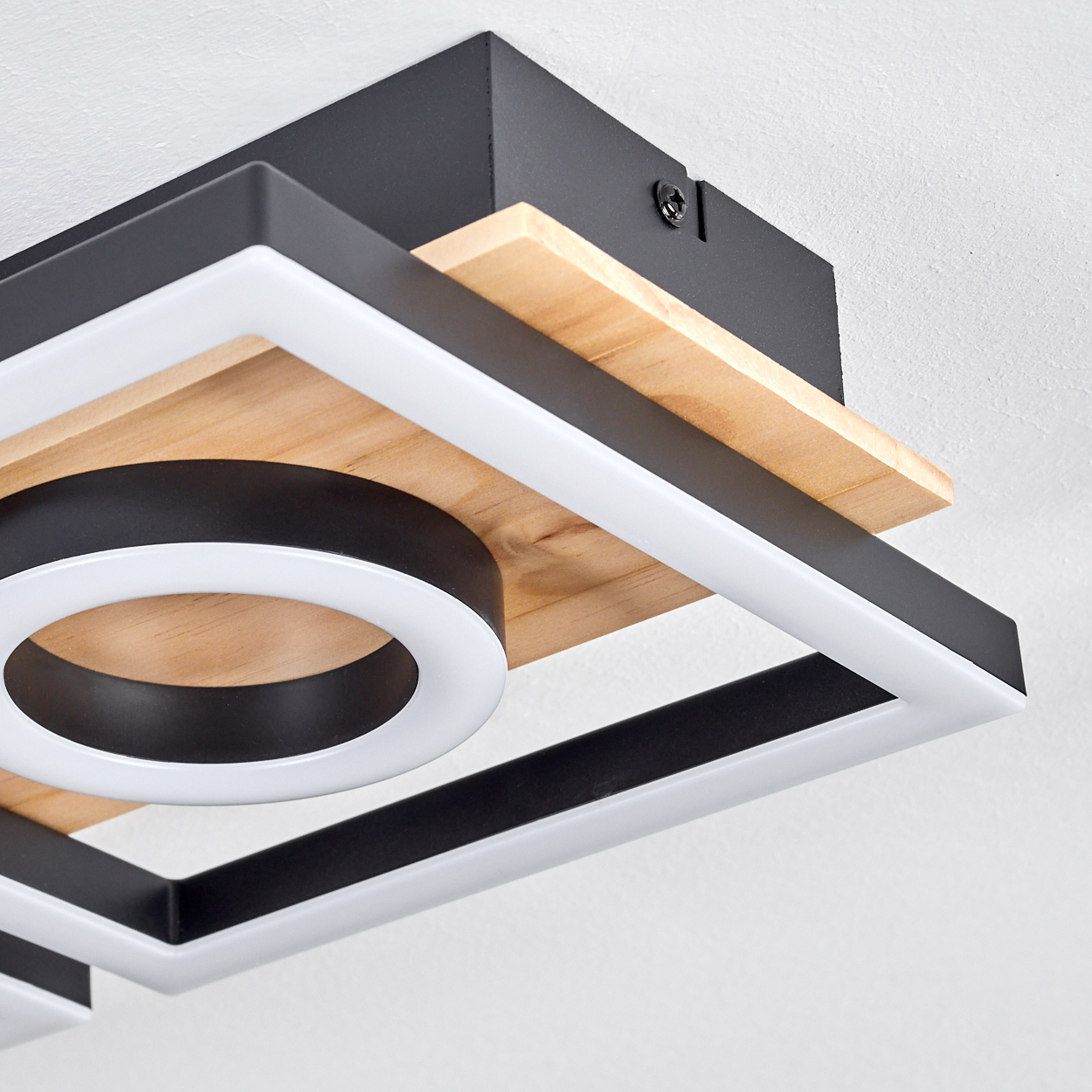 Nahaufnahme einer modernen Deckenleuchte. Schwarzer und weißer quadratischer Rahmen mit Holzpaneel und kreisförmigem Licht.