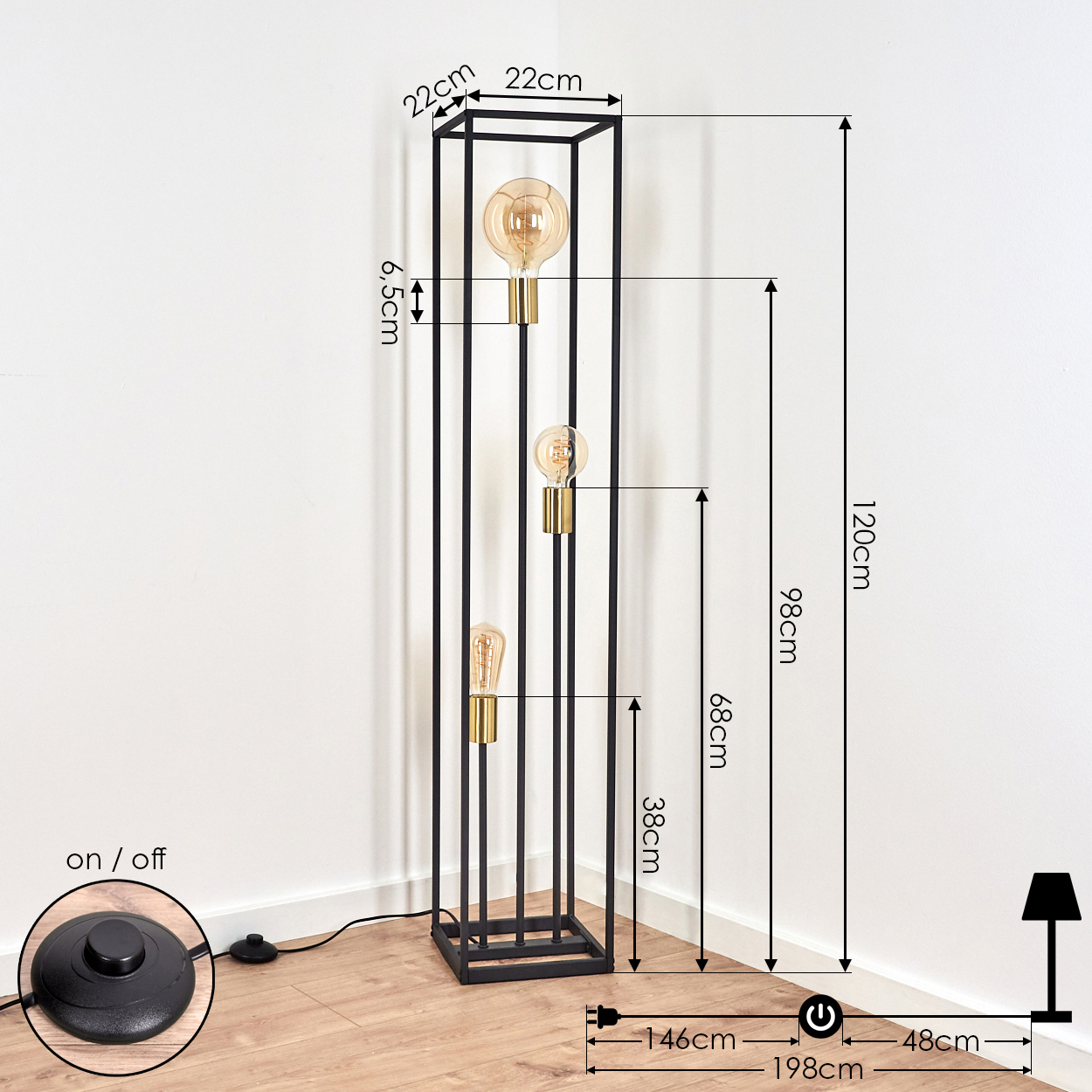 Schwarze Metall-Stehlampe mit drei Glühbirnen, Fußschalter und Maßangaben vor weißer Wand und Holzboden.