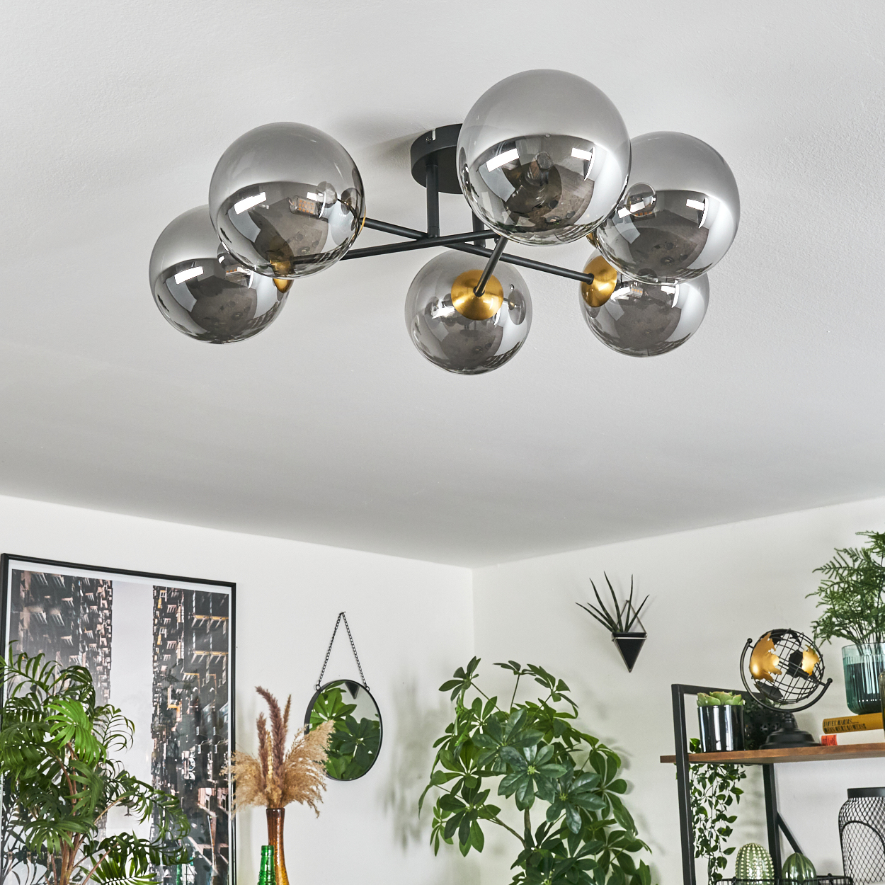 Moderne Deckenleuchte mit sechs grauen Glaskugeln. Der Raum hat Pflanzen, einen Spiegel und ein Bild. Der Hintergrund ist weiß.