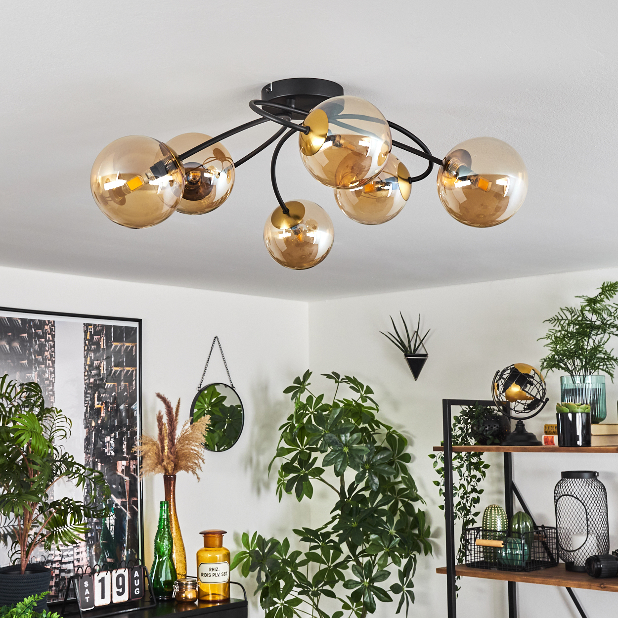 Moderne Deckenleuchte mit mehreren goldfarbenen Glaskugeln. Der Raum hat Pflanzen, einen Spiegel und Regale mit Dekor.