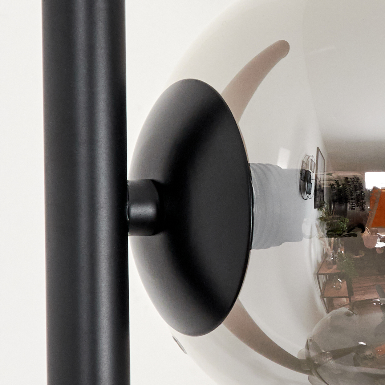 Nahaufnahme einer modernen Lampe. Die Lampe hat einen schwarzen Metallstiel, einen schwarzen Lampenschirm und einen großen, transparenten Glaskolben.