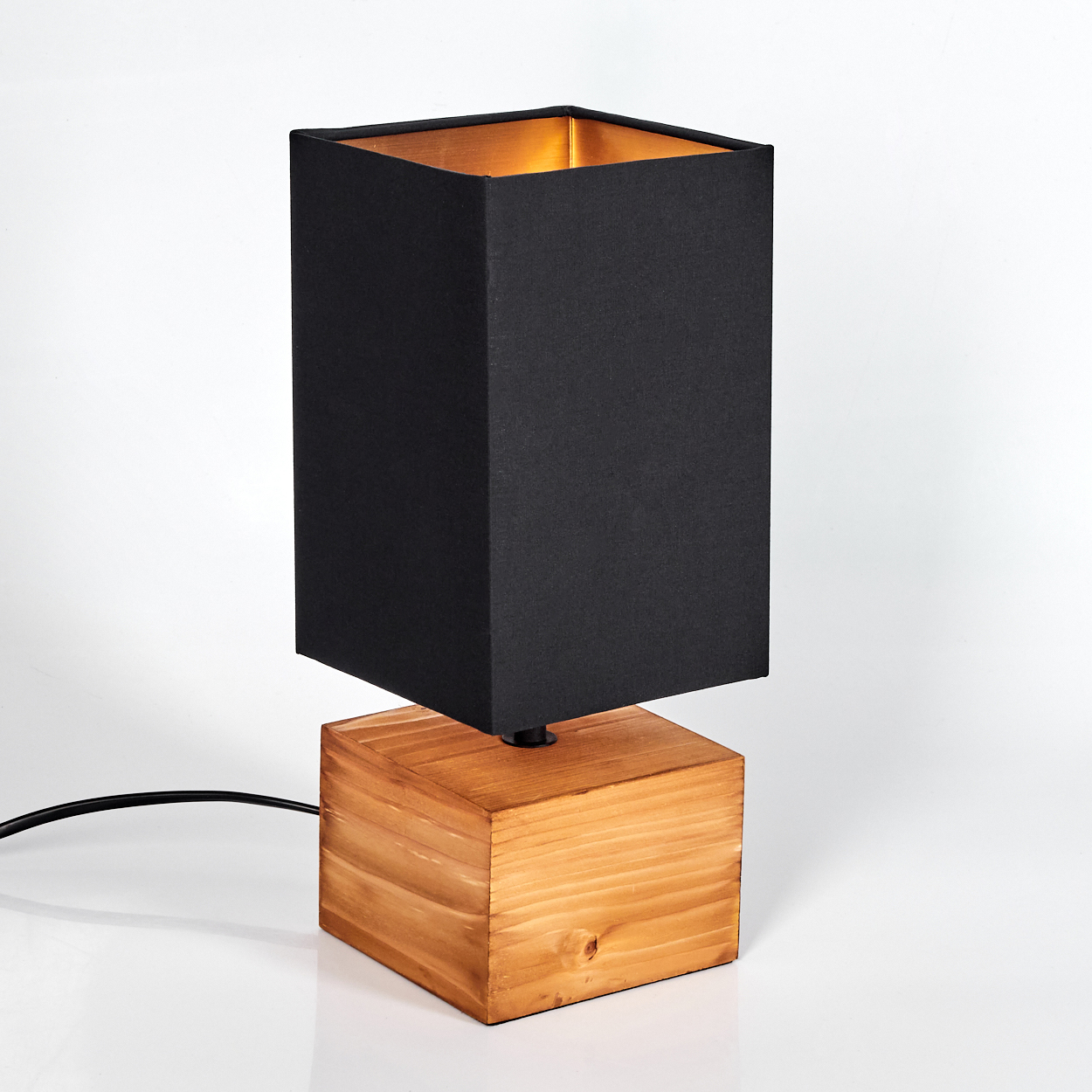 Eine schwarze, quadratische Lampe mit Holzsockel. Die Innenseite der Lampe ist goldfarben. Ein schwarzes Kabel ist angebracht. Der Hintergrund ist weiß.