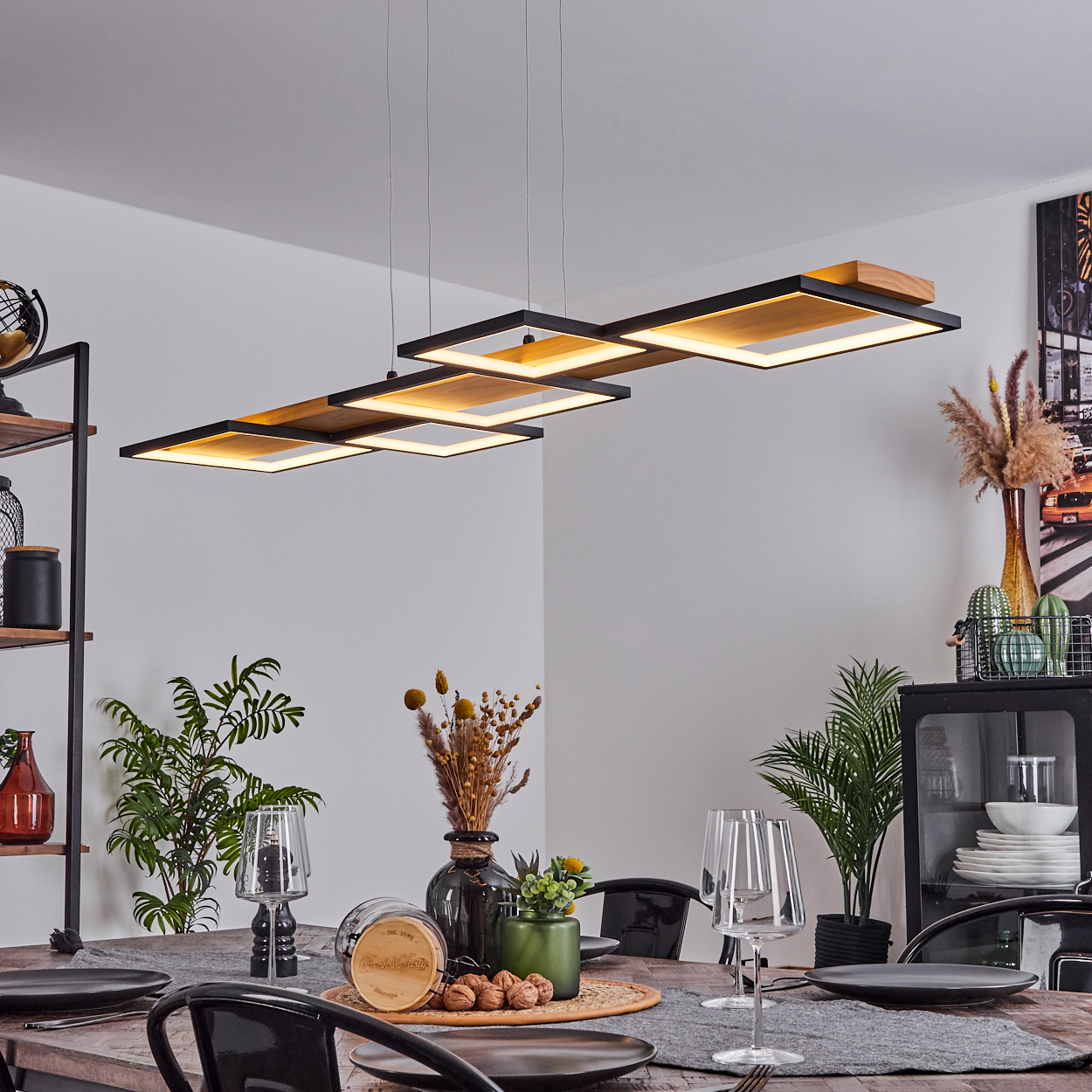 Esszimmer mit Holztisch, schwarzen Stühlen und moderner Leuchte. Pflanzen und Dekorationen sind vorhanden.