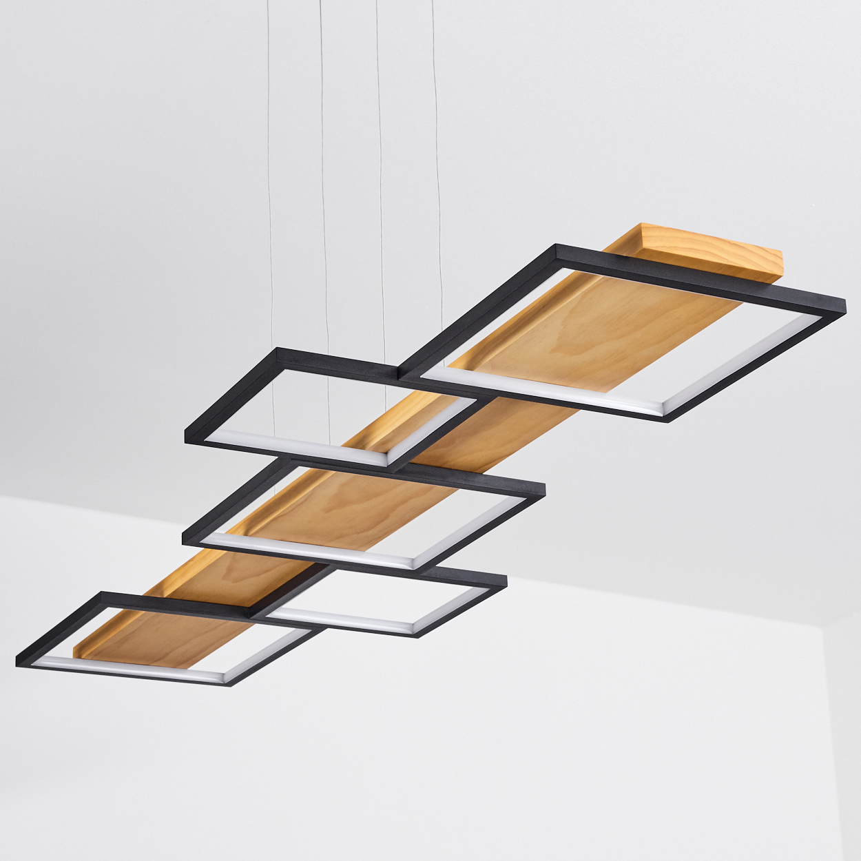 Moderne Hängeleuchte mit schwarzen Quadratrahmen, Holzpaneelen und weißem Innenraum. An der Decke vor weißem Hintergrund abgehängt.