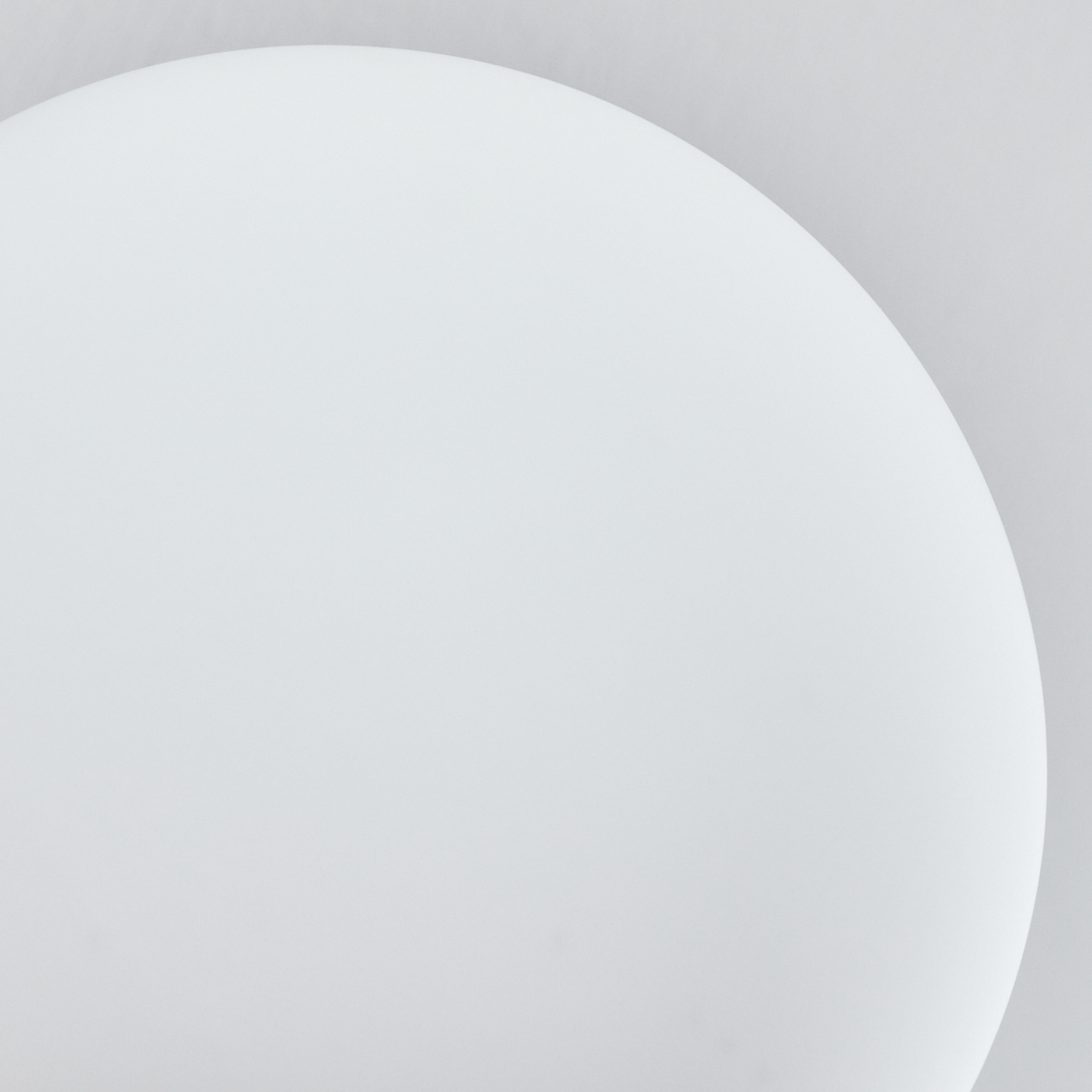 Eine weiße, gebogene Form dominiert, wahrscheinlich ein Tisch oder eine Oberfläche, vor einem hellgrauen Hintergrund. Glatte, saubere Linien, schlichtes Design.