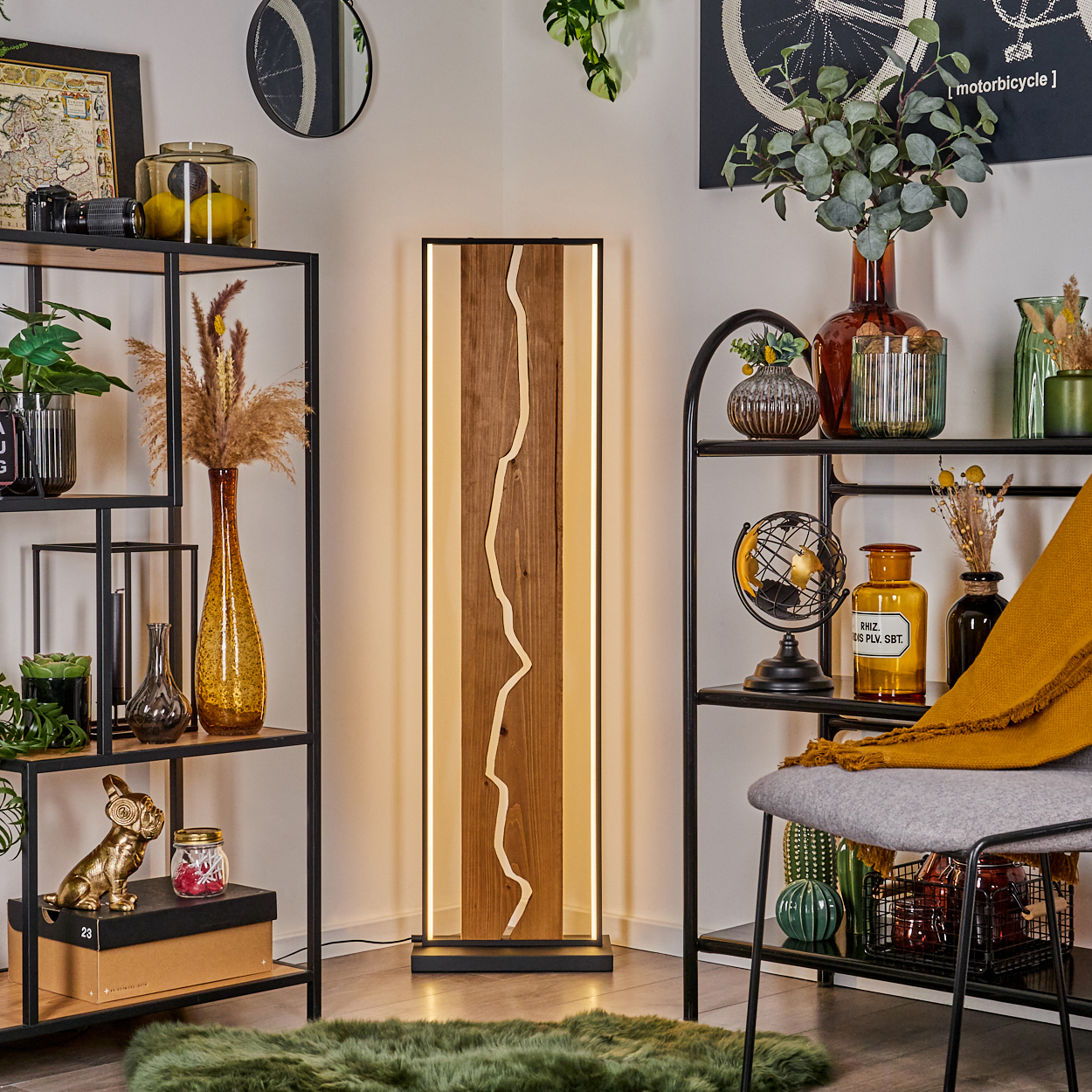Eine Zimmerecke mit einer Holzlampe, Regalen mit Dekoration, einem grünen Teppich und einem Stuhl mit gelber Decke.