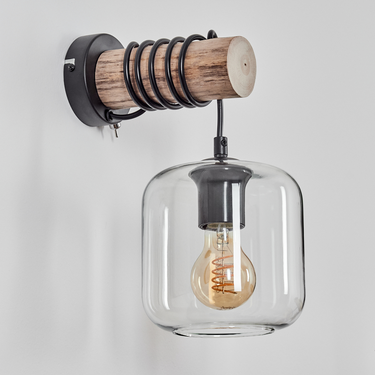 Eine Wandlampe mit Holzsockel, schwarzem Metallrahmen und Glasschirm mit sichtbarer Glühbirne.
