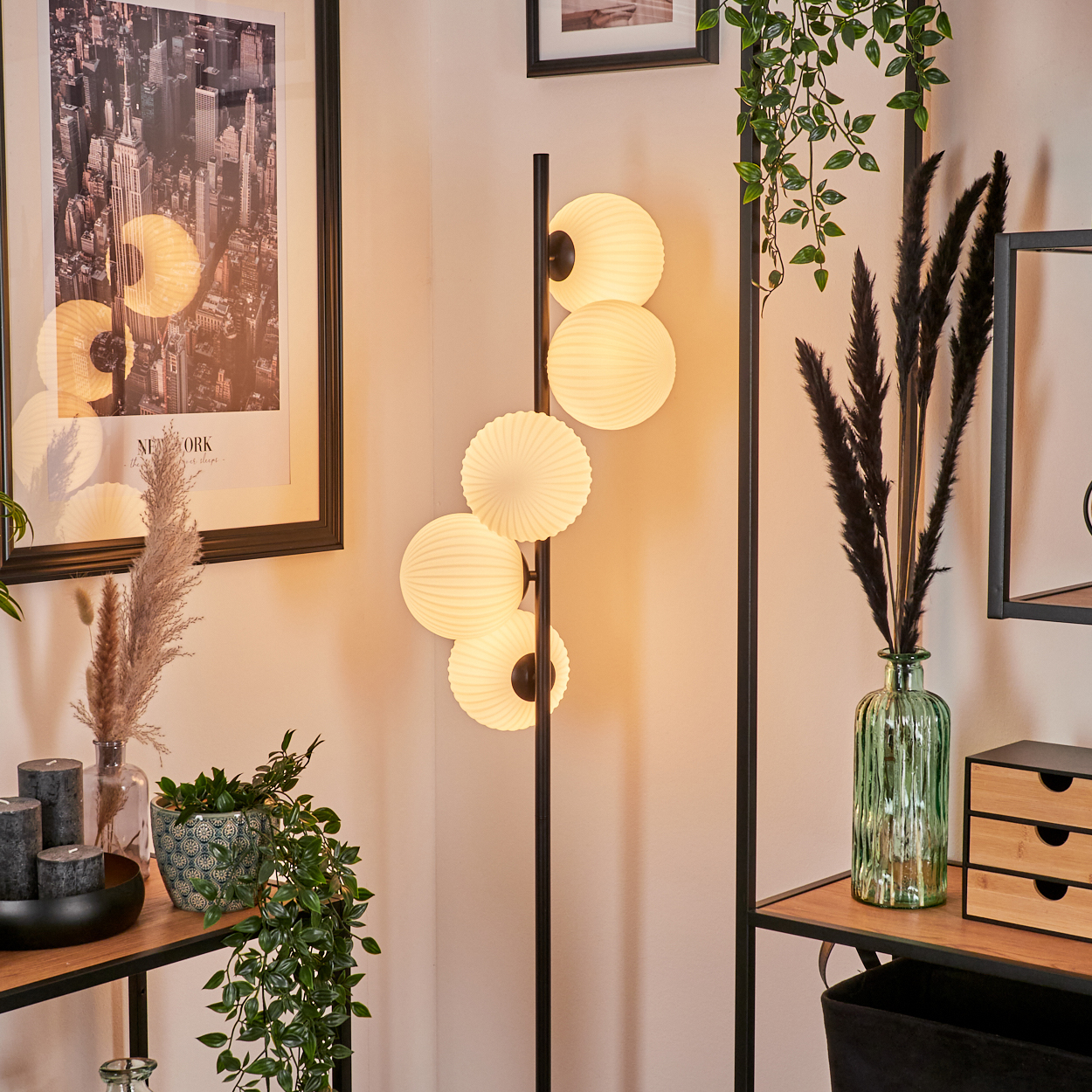 Eine moderne Wohnzimmerecke mit Stehlampe, Kugel-Leuchten, Pflanzen, gerahmter Stadtansicht und dekorativen Elementen.
