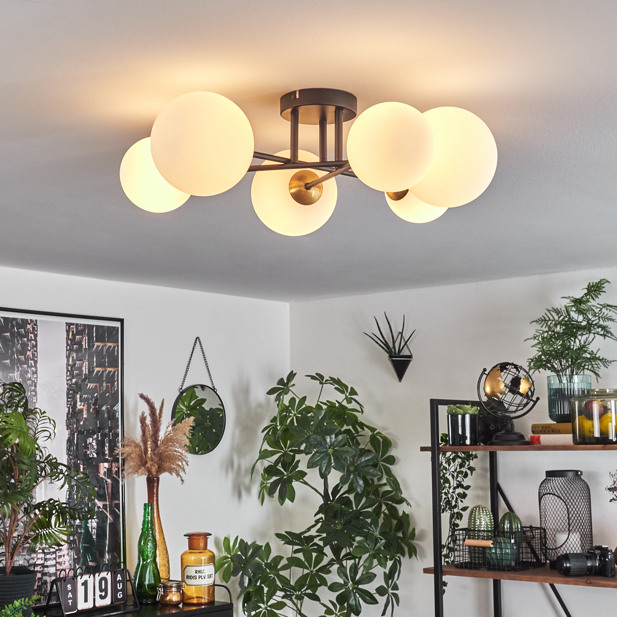Eine moderne Deckenleuchte mit kugelförmigen Glühbirnen. Der Raum hat Pflanzen, einen Spiegel und ein Regal mit Dekorationen. Die Ästhetik ist modern.