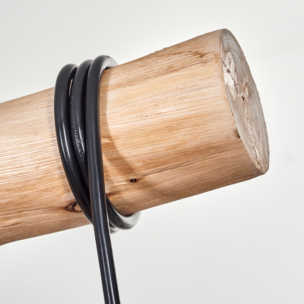 Ein schwarzes Kabel ist um einen Holzstamm gewickelt, vor einem weißen Hintergrund. Der Stamm ist hellbraun mit sichtbarer Holzmaserung.
