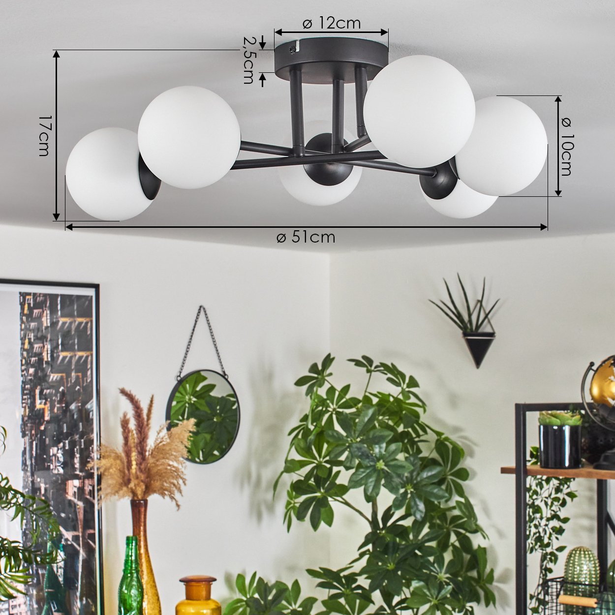 Eine schwarze Deckenlampe mit fünf weißen Kugeln. Darunter ein Raum mit Pflanzen, einem Spiegel und einem Regal mit Dekoration.