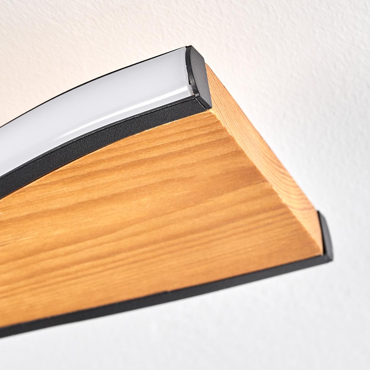 Nahaufnahme einer Holzlampe mit schwarzem Rand und weißem Lichtstreifen. Das Holz hat eine natürliche Maserung. Der Hintergrund ist weiß.