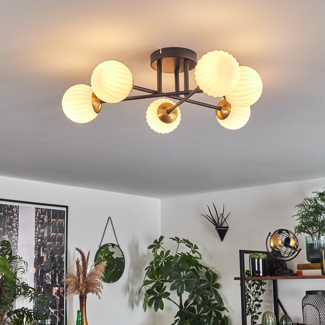Deckenleuchte mit sechs kugelförmigen Lampen. Raum hat Pflanzen, Spiegel und Globus. Weiße Decke und Wände sind sichtbar.