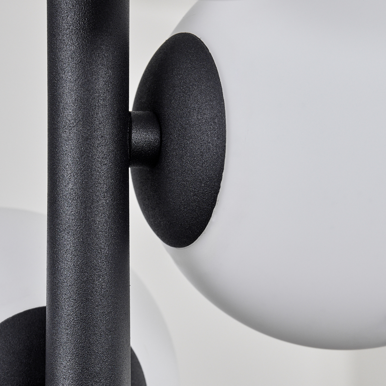 Nahaufnahme einer modernen Lampe. Schwarze Metallstange, weißes Kugellicht und schwarze kreisförmige Halterungen auf weißem Hintergrund.