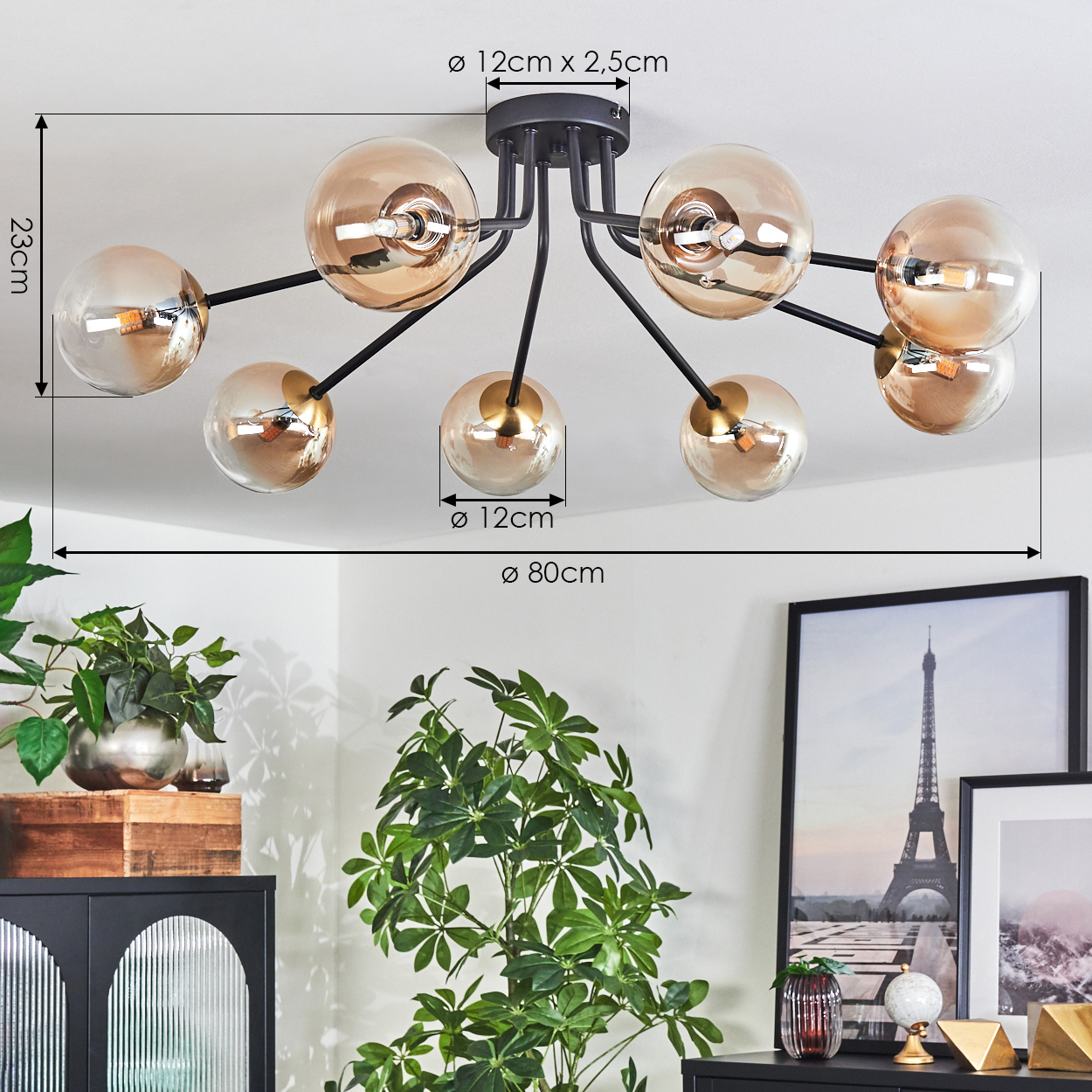 Deckenlampe mit acht Kugeln, schwarzen Armen und bernsteinfarbenem Glas. Pflanzen und gerahmte Kunst im Hintergrund.