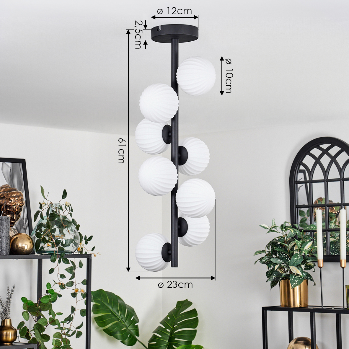 Eine schwarz-weiße moderne Pendelleuchte mit weißen Kugelleuchten. Die Leuchte hängt in einem Raum mit Pflanzen und Dekorationen.