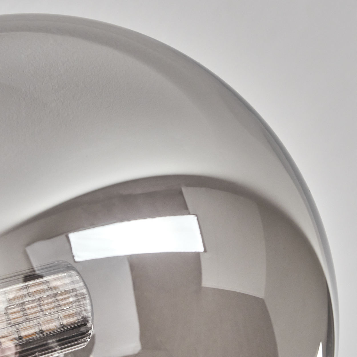 Nahaufnahme einer klaren Glaskugel mit reflektierender Oberfläche. Im Inneren der Kugel ist ein Licht zu sehen. Der Hintergrund ist weiß.