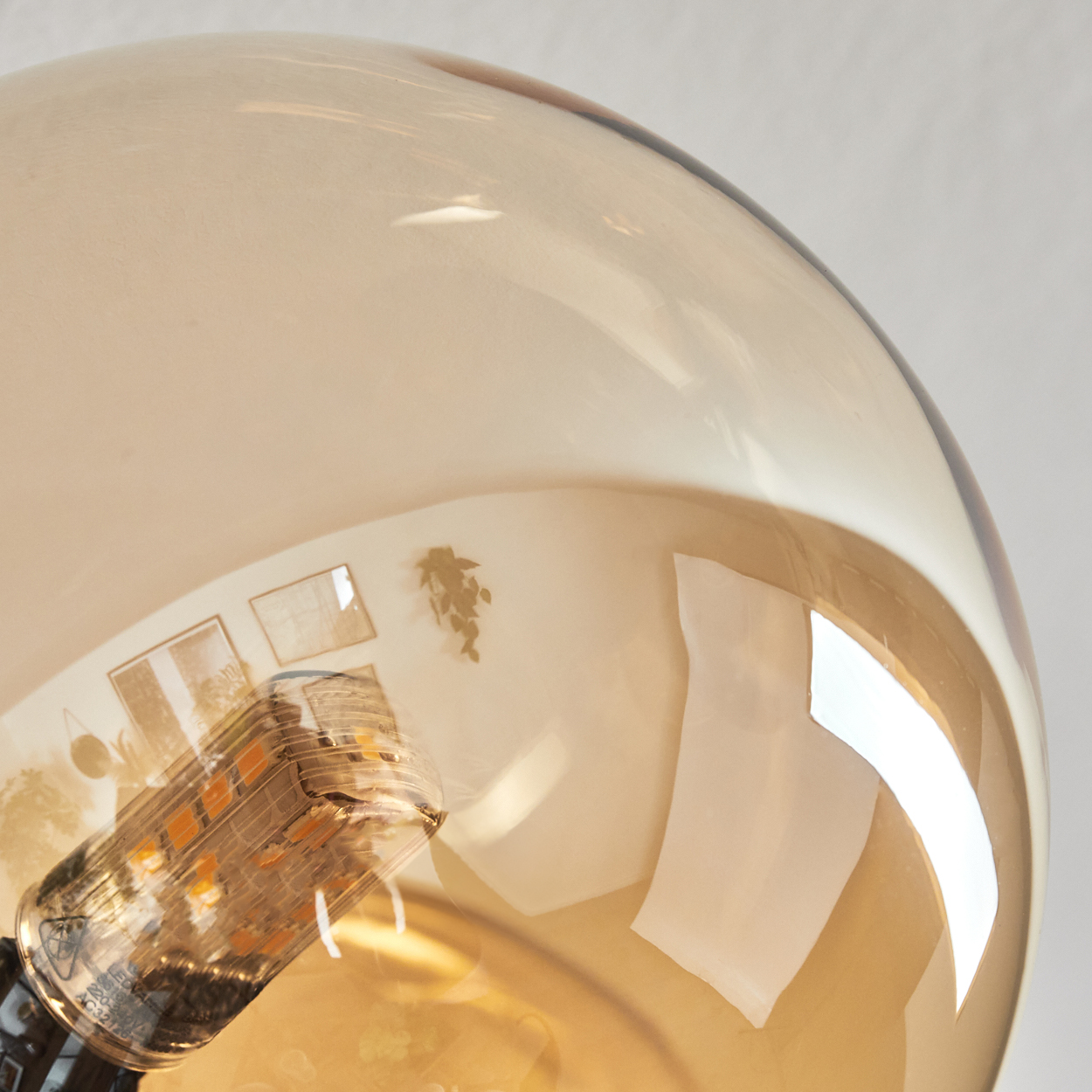 Nahaufnahme einer Glühbirne. Die Glühbirne ist in einem transparenten, bernsteinfarbenen Glas eingeschlossen. Im Inneren ist eine LED-Leuchte sichtbar.