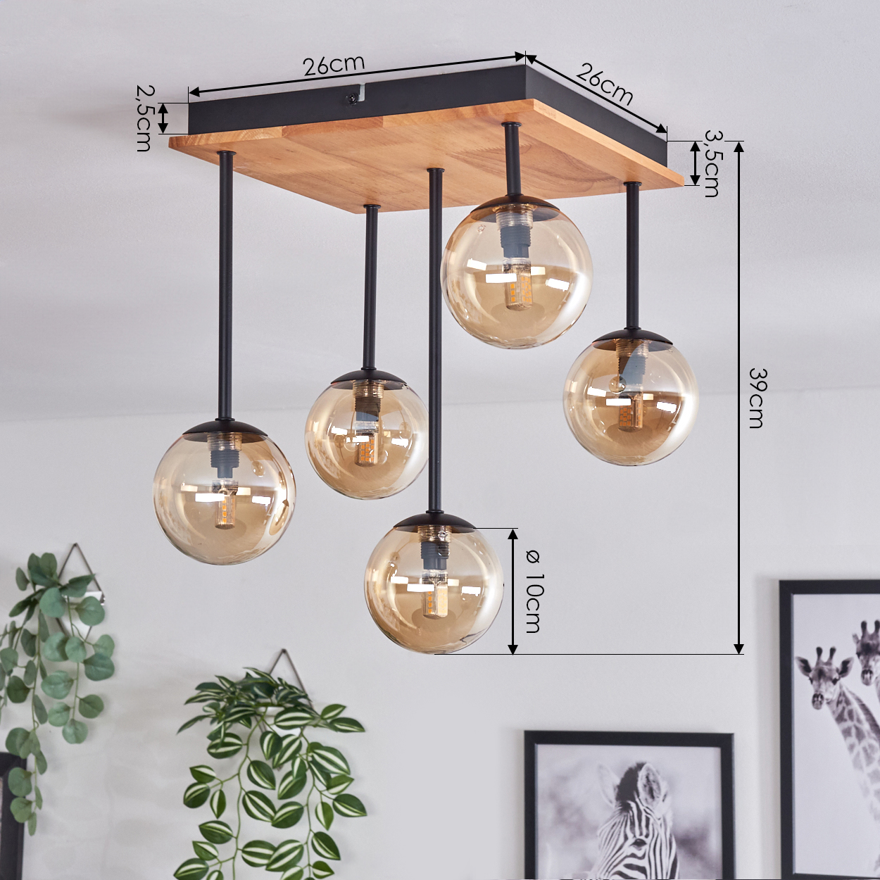 Deckenleuchte mit Holzsockel, fünf bernsteinfarbene Glaskugelschirme. Schwarze Metallstangen. Maße und dekorative Pflanzen im Hintergrund.