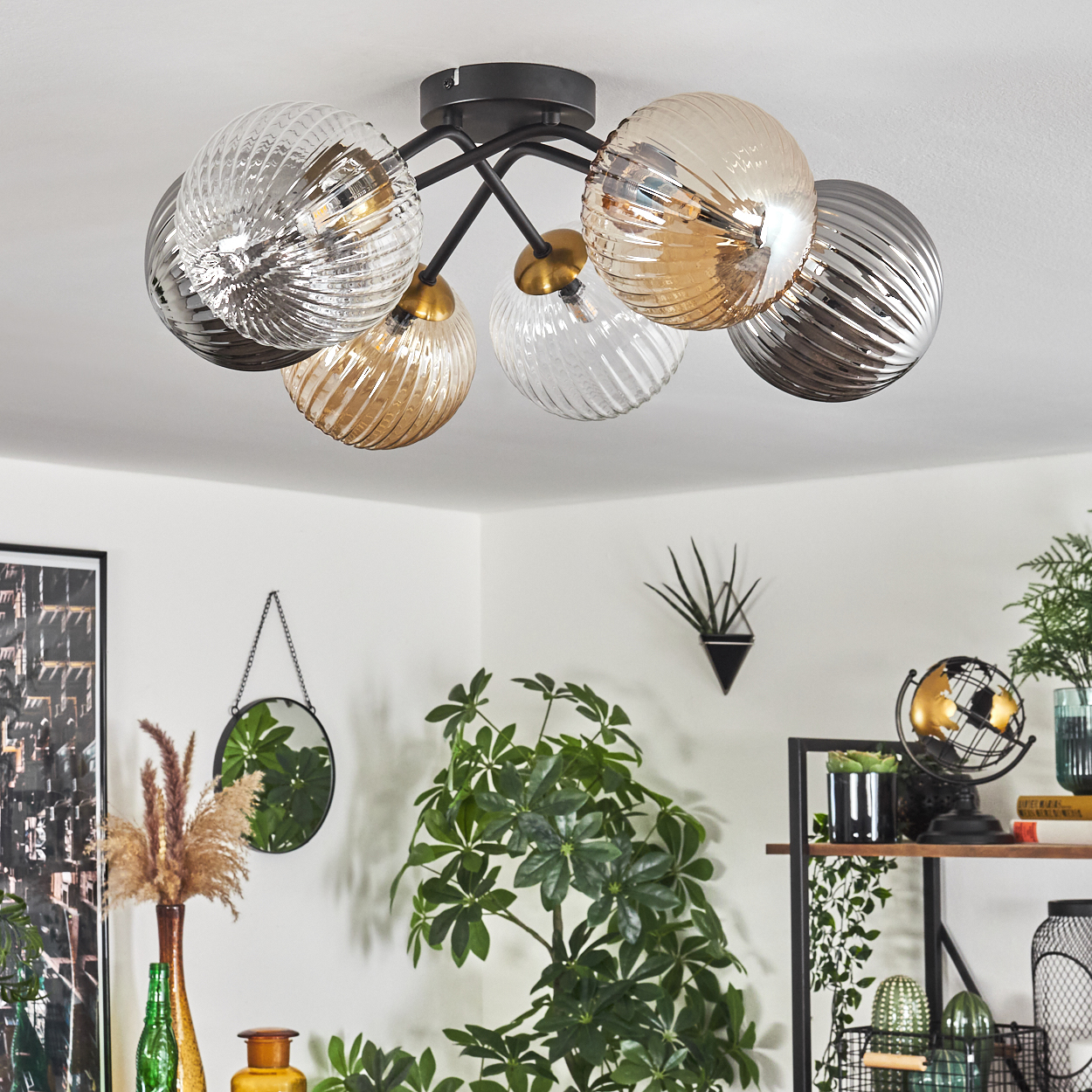 Deckenleuchte mit sechs Glaskugelschirmen. Raum mit Pflanzen, Spiegel und Regalen. Licht hat goldene und klare Kugeln.