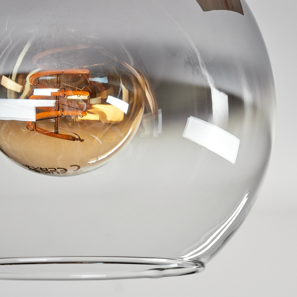 Nahaufnahme einer Glühbirne mit klarem Glasschirm. Der Glühfaden der Glühbirne ist sichtbar.