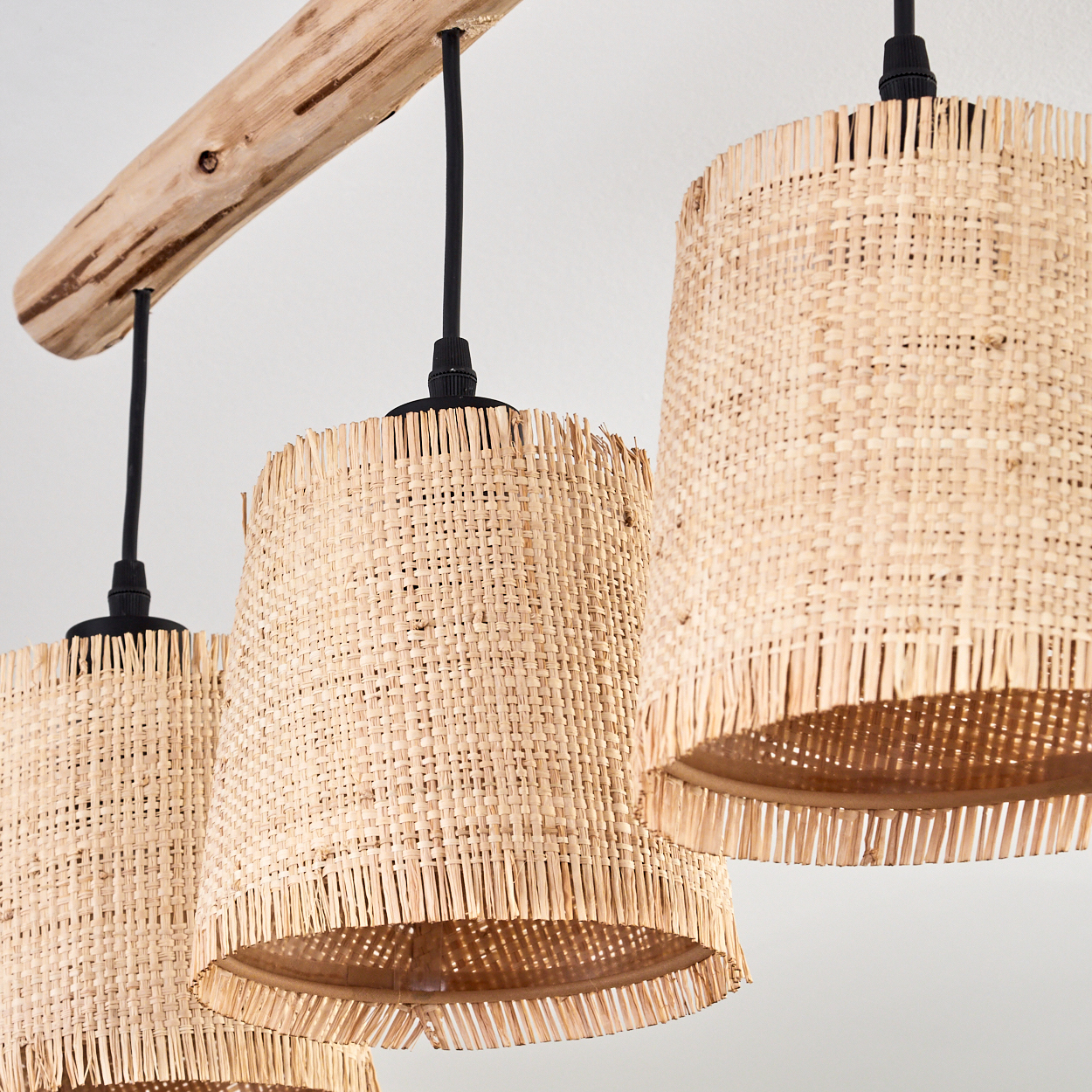 Drei gewebte Lampenschirme hängen an einem Holzbalken. Die Schirme sind beige, mit schwarzen Kabeln und Armaturen auf weißem Hintergrund.