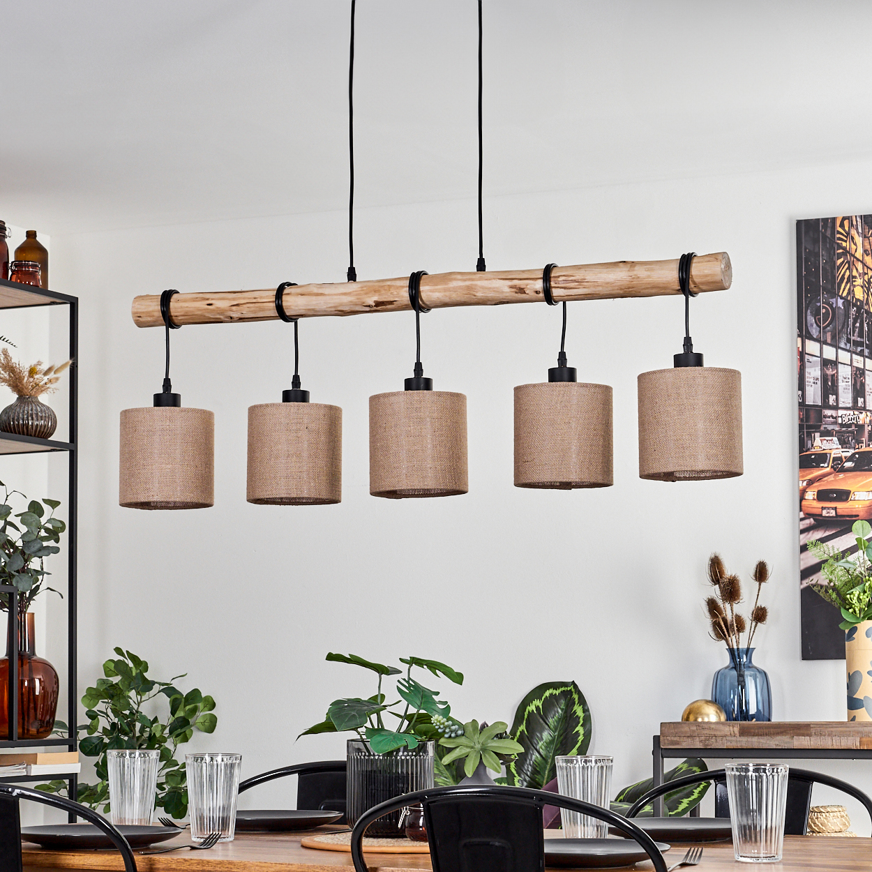 Esszimmer mit Holzbalken-Pendelleuchten, Tisch mit Gläsern, Tellern und Pflanzen. Kunstwerk an der Wand, Regale mit Vasen.