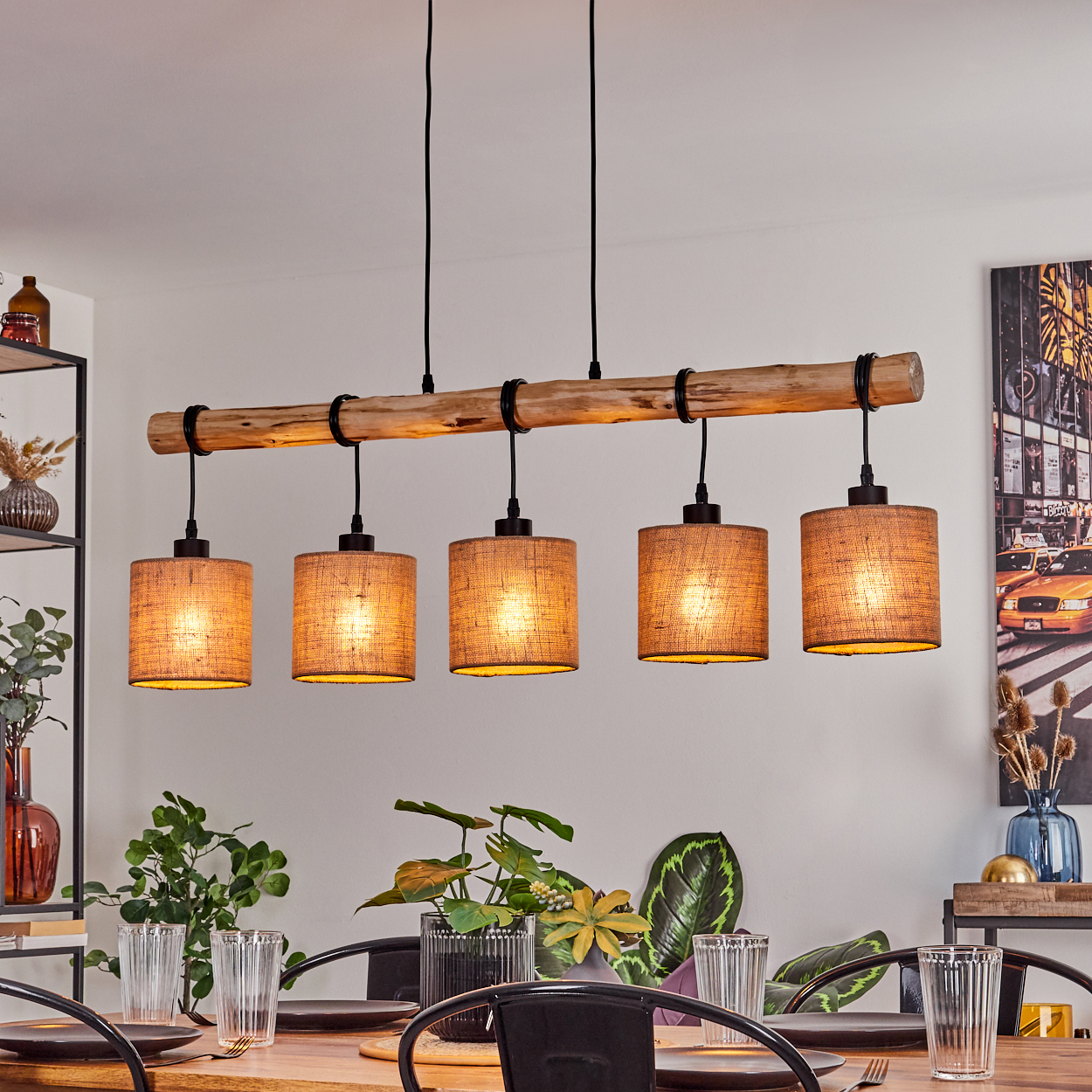 Ein Esszimmer mit einer Holzbalken-Lichtanlage mit fünf Lampenschirmen. Pflanzen und ein Tisch sind sichtbar, mit einem Gemälde einer Stadtszene im Hintergrund.