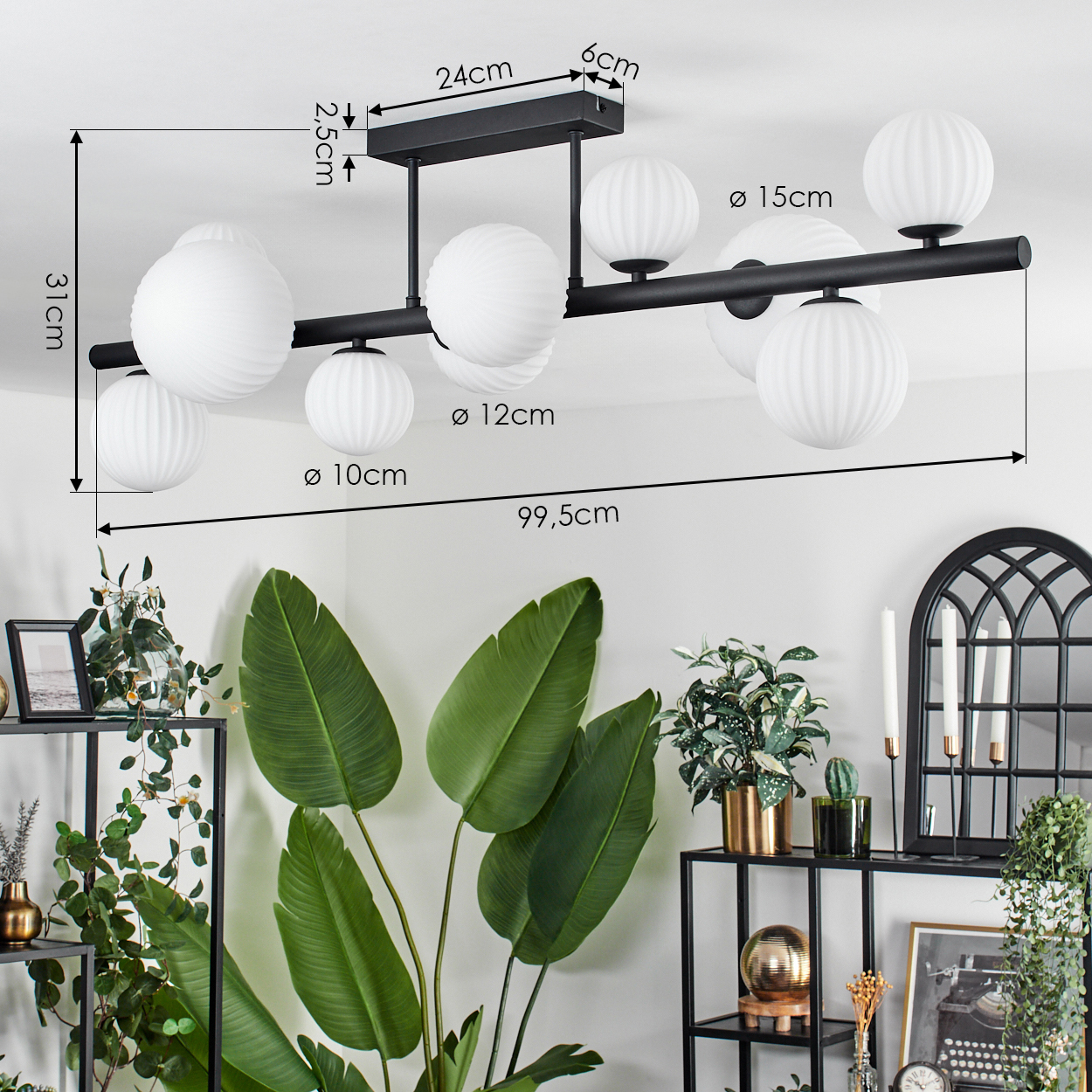 Eine schwarze Deckenlampe mit weißen Kugelschirmen. Im Hintergrund grüne Pflanzen und schwarze Metallregale.